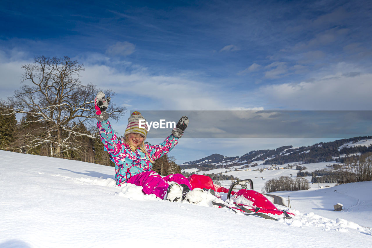 Girl on snow covered field against sky