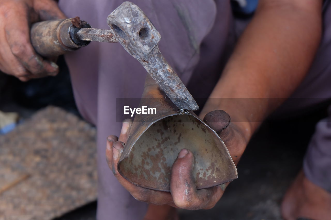 cropped hand of man working on metal