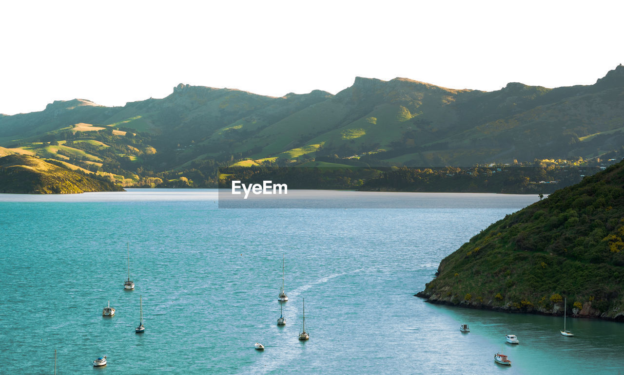 Scenic view of sea by mountains against sky