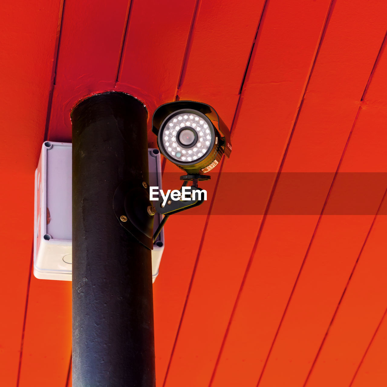 Low angle view of security camera against red ceiling