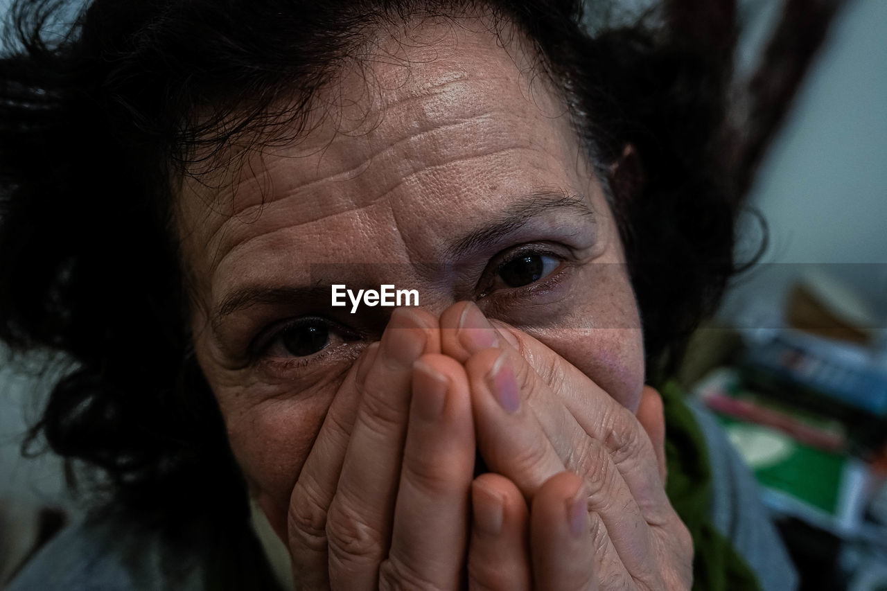 Close-up portrait of woman with hands covering mouth