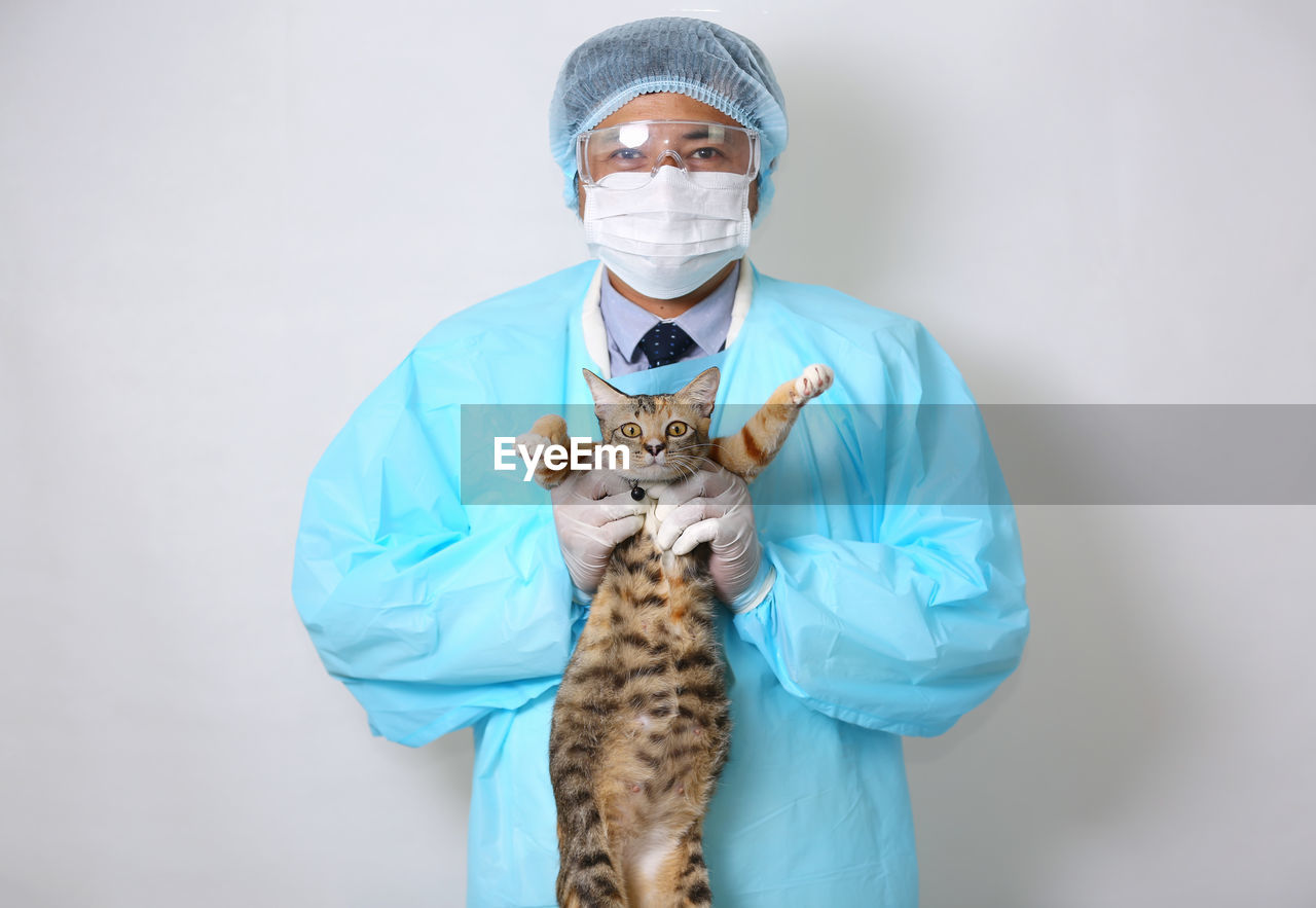 Portrait of doctor holding cat against white background