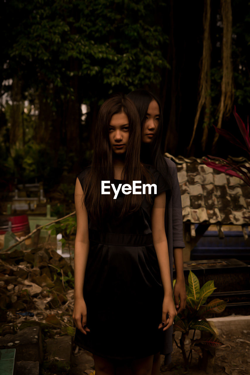 Portrait of young woman standing against plants