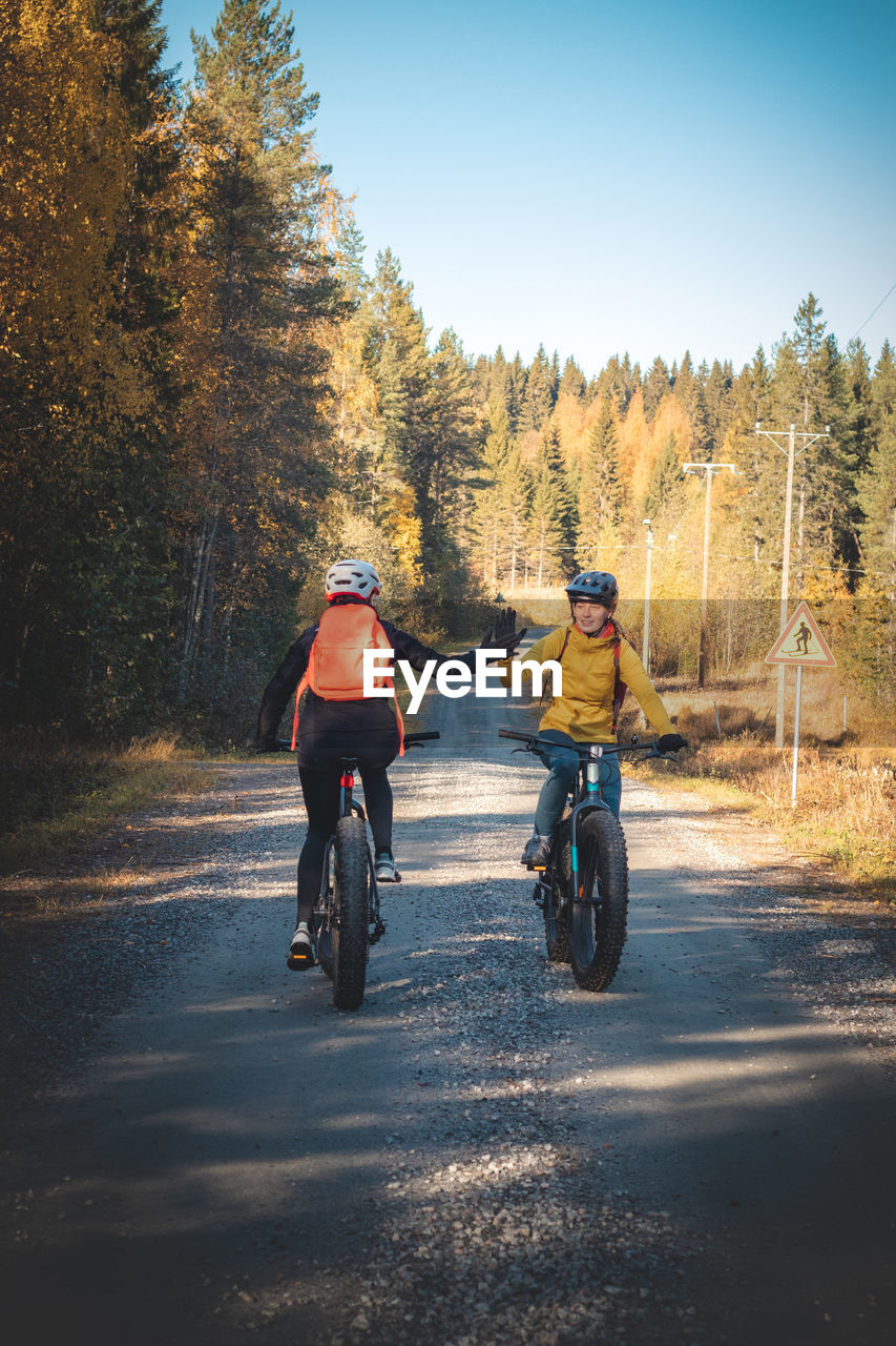 Cycling friends greet each other as they meet on a dirt road in vuokatti area, kainuu, finland.