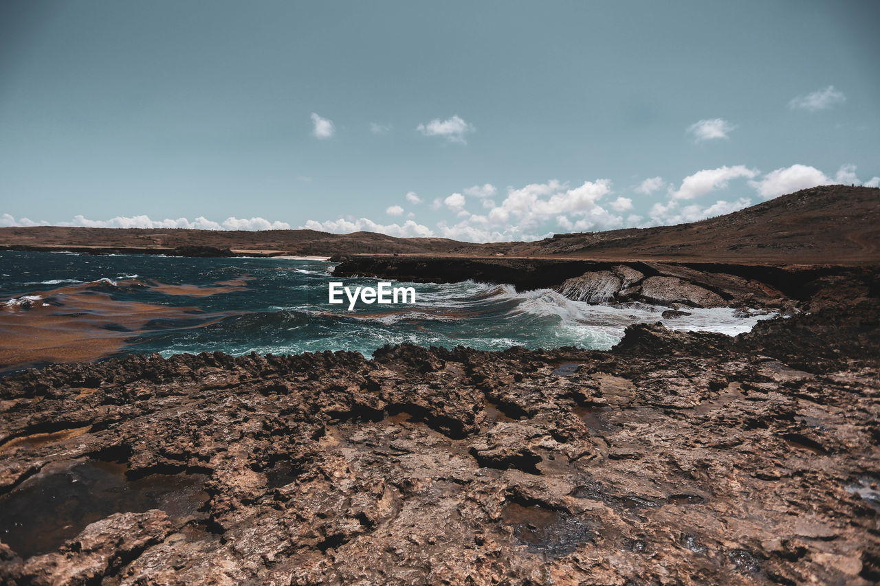 Scenic view of rocks on beach against sky