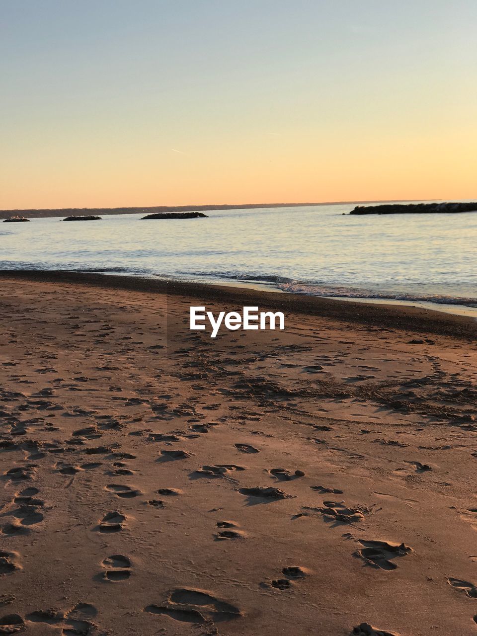 SCENIC VIEW OF BEACH AGAINST CLEAR SKY AT SUNSET