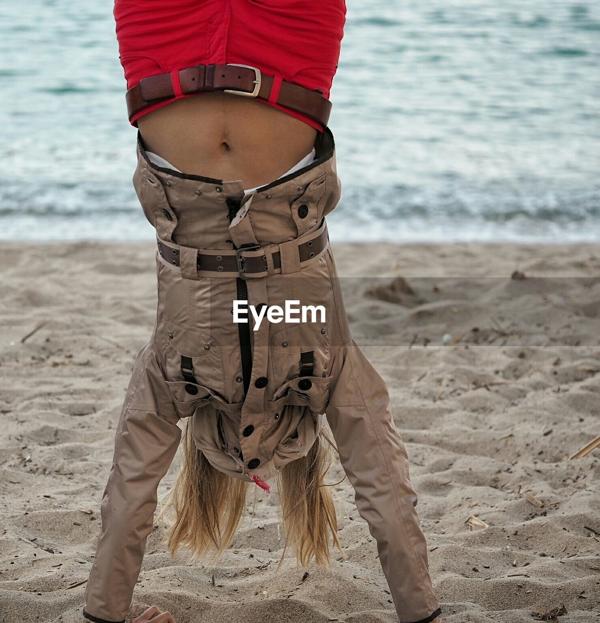 Young woman doing handstand on sand at beach
