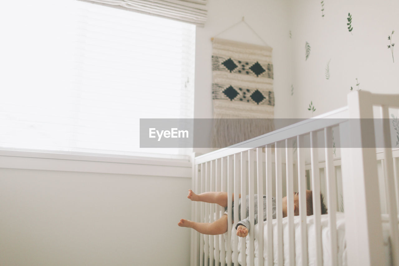 Baby boy lying in crib at home