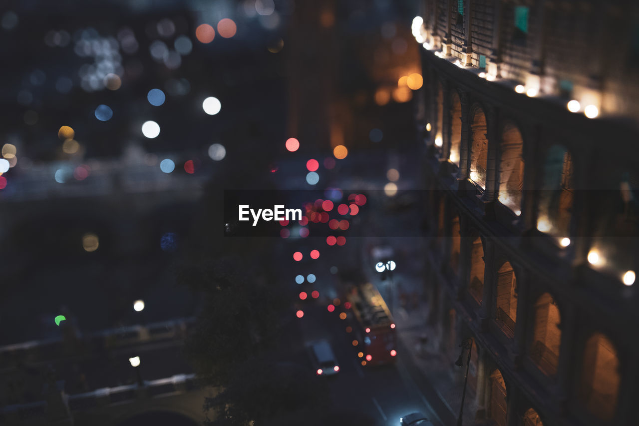 DEFOCUSED IMAGE OF ILLUMINATED STREET IN CITY AT NIGHT