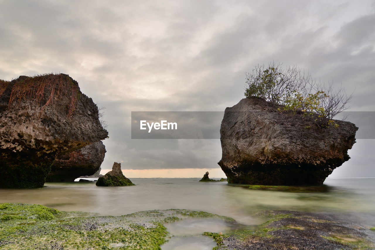 Rocks on sea shore against sky