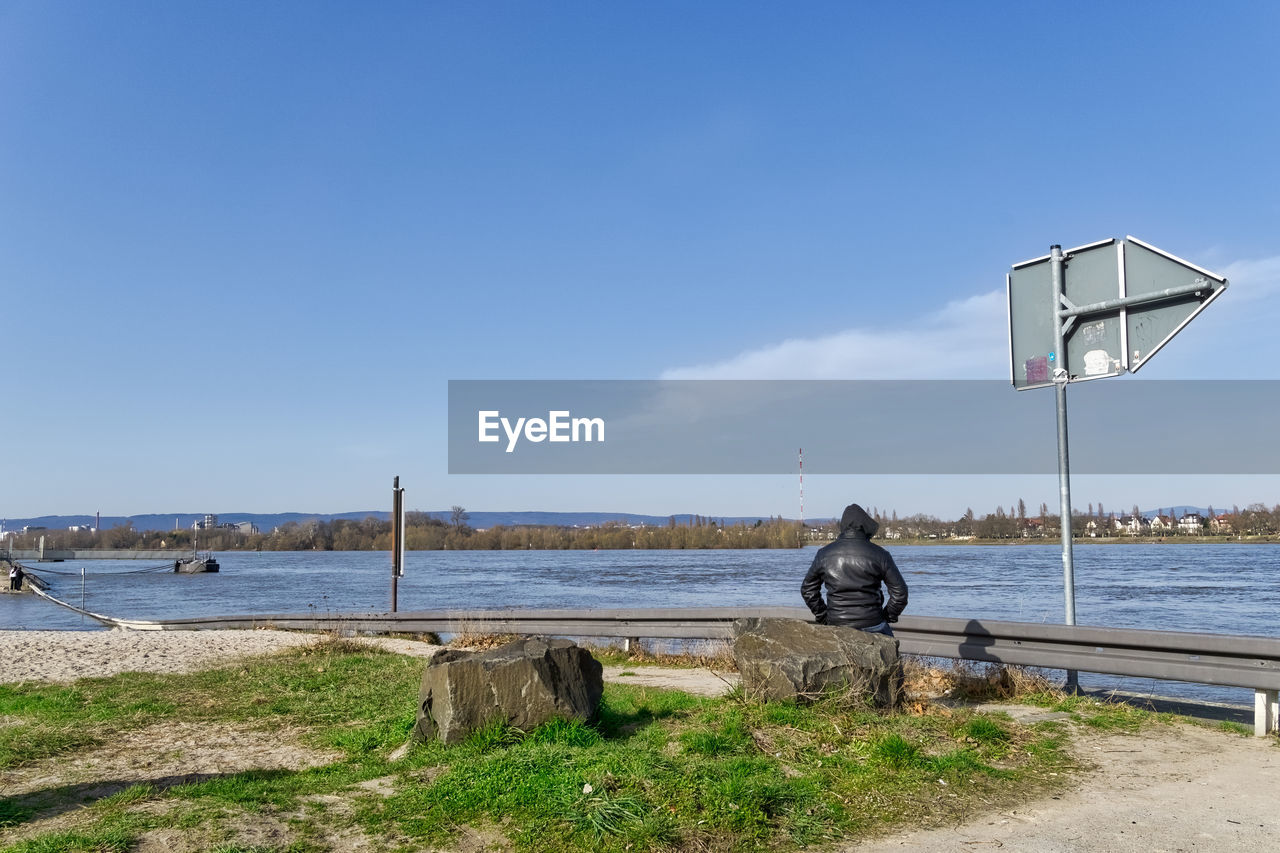 View of road sign by sea against sky