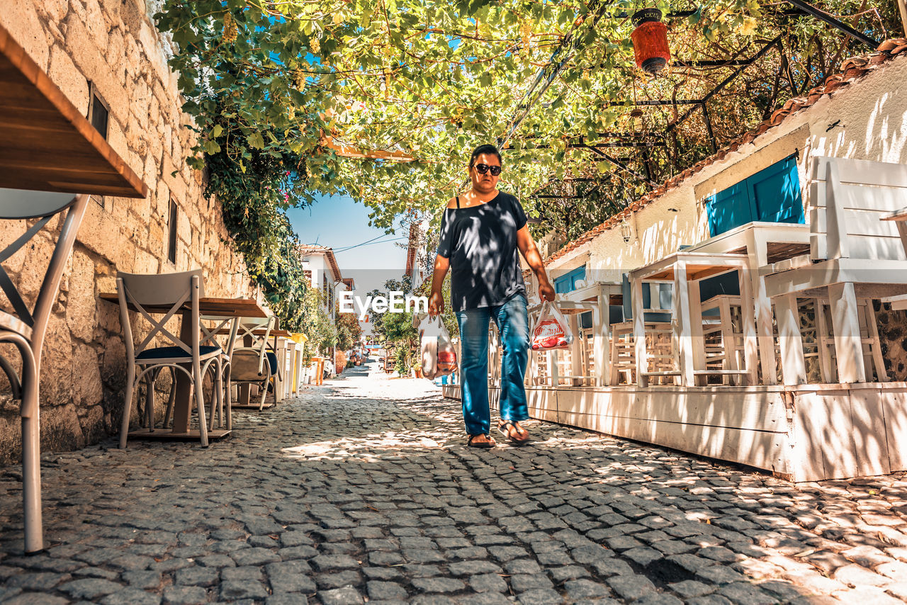 MAN STANDING ON FOOTPATH AGAINST BUILDING