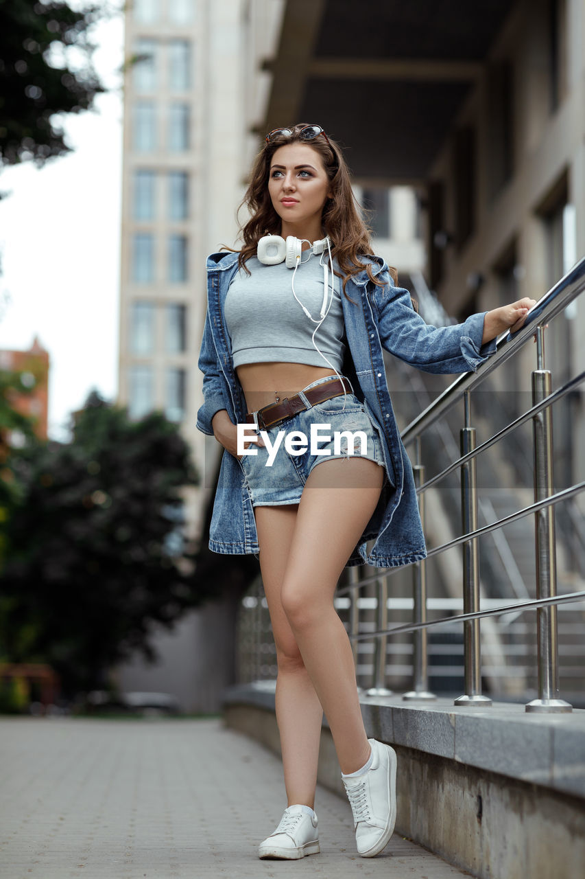 portrait of young woman sitting on staircase in city