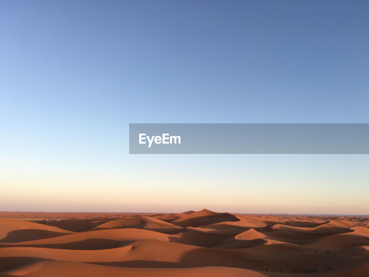 Scenic view of desert against clear blue sky