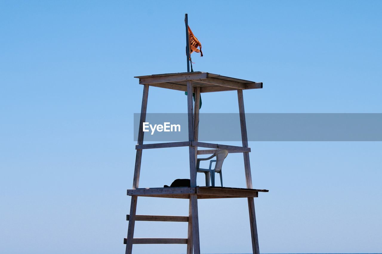 Low angle view of lifeguard chair against clear blue sky