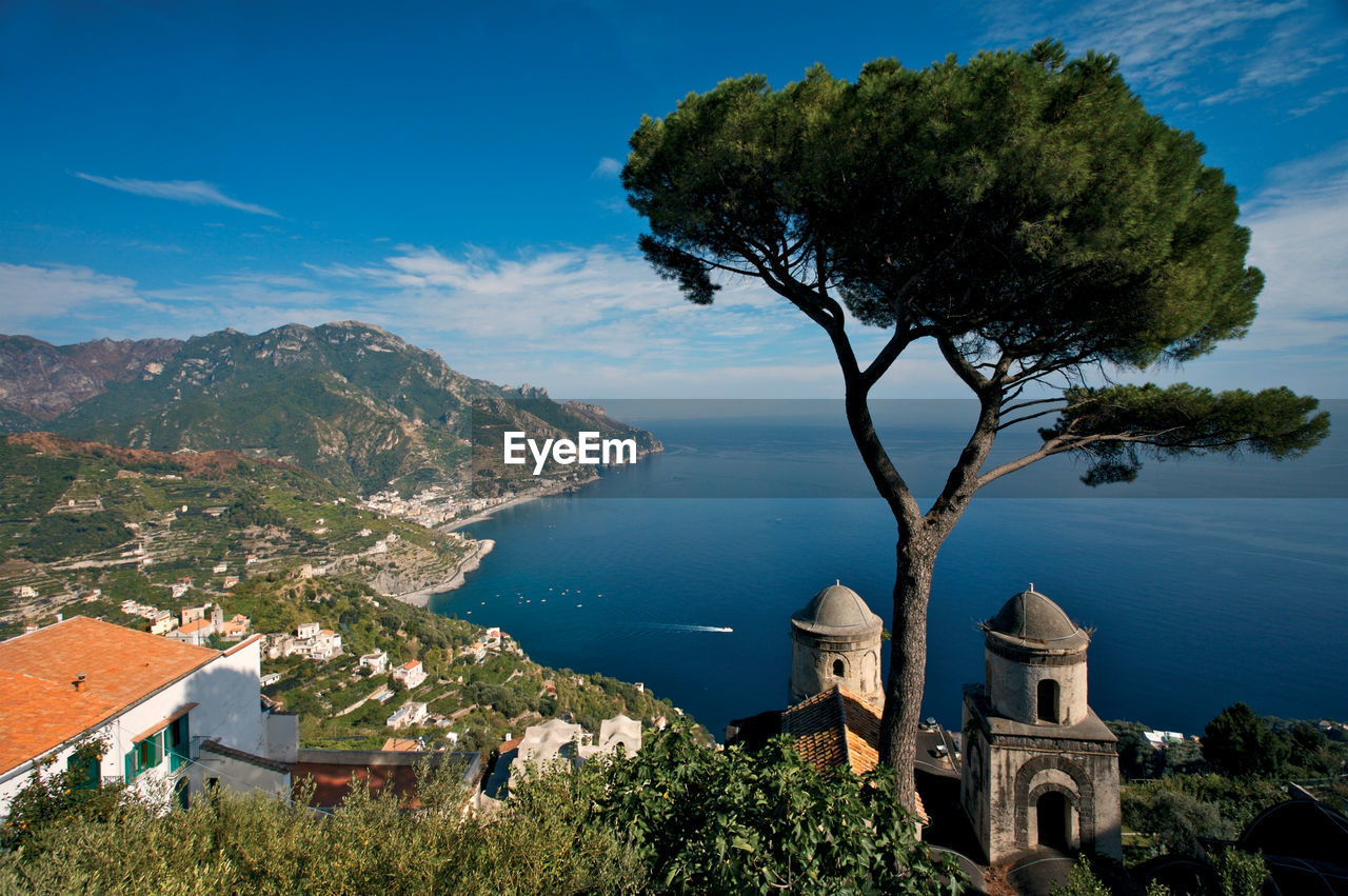 High angle view of houses on cliff by sea against blue sky during sunny day