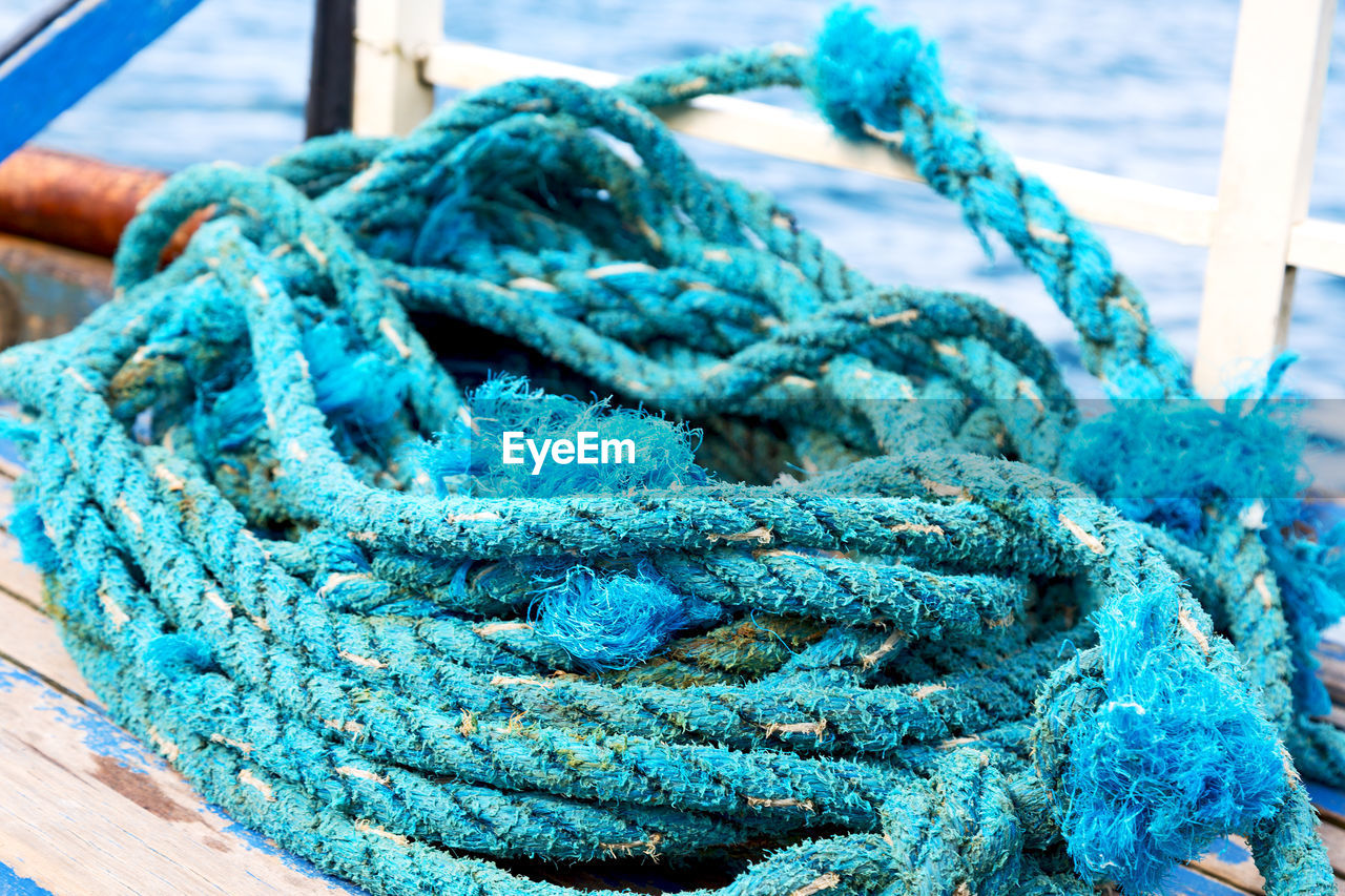 CLOSE-UP OF BLUE ROPE TIED TO FISHING NET