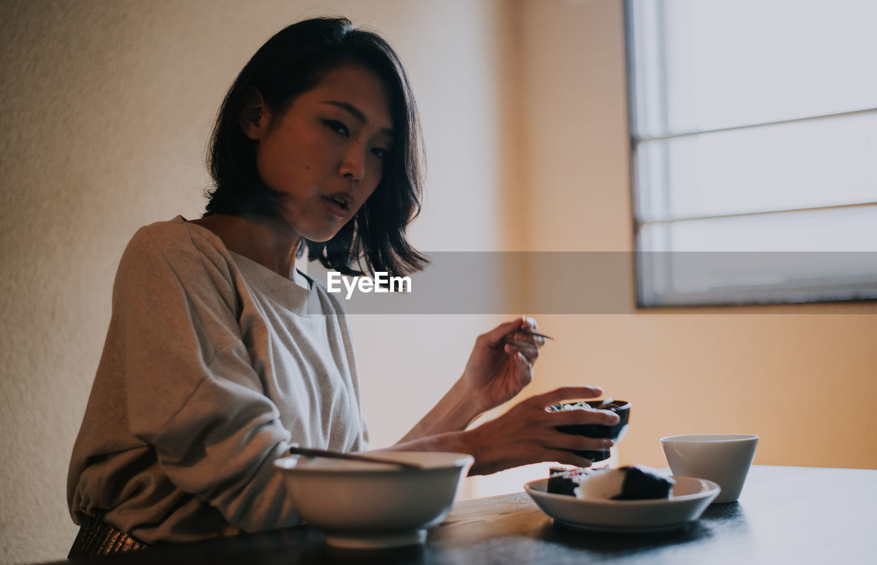 Beautiful woman eating food sitting at home