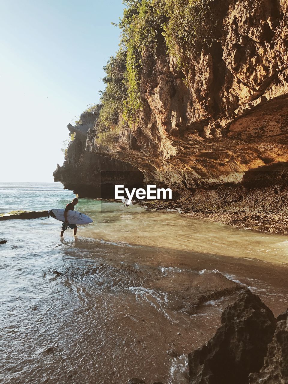 MAN ON ROCKS BY SEA AGAINST SKY