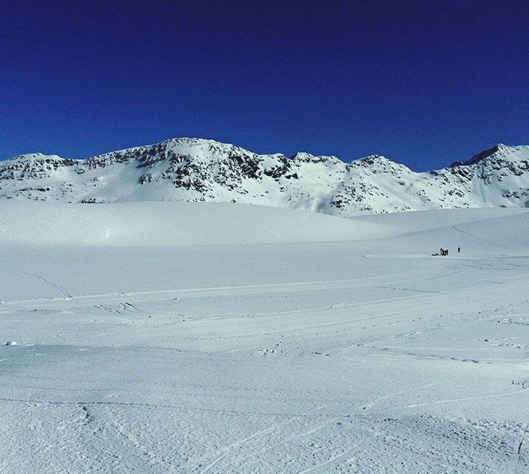 Snow field against clear blue sky