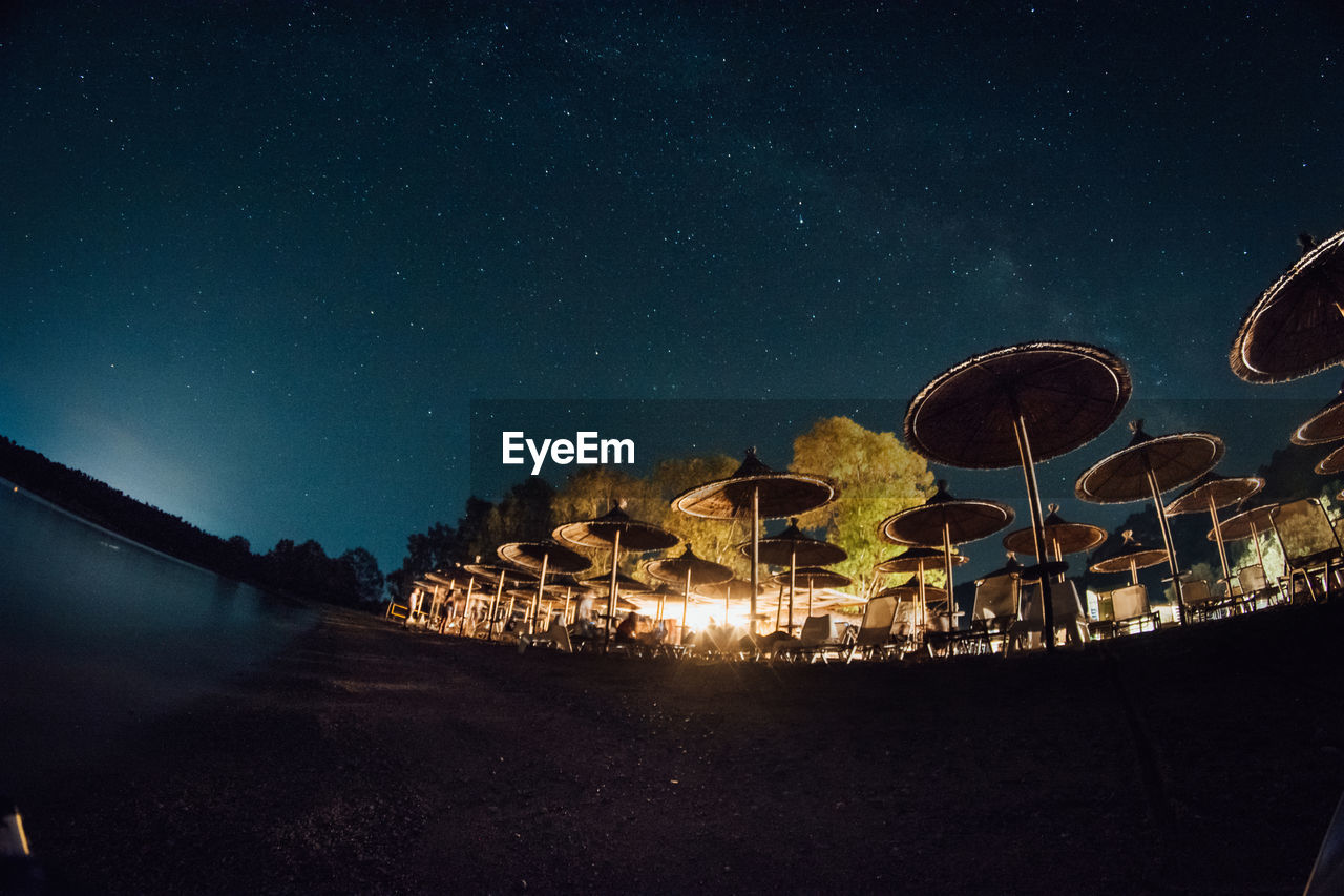 Low angle fish-eye lens shot of parasols against sky at night