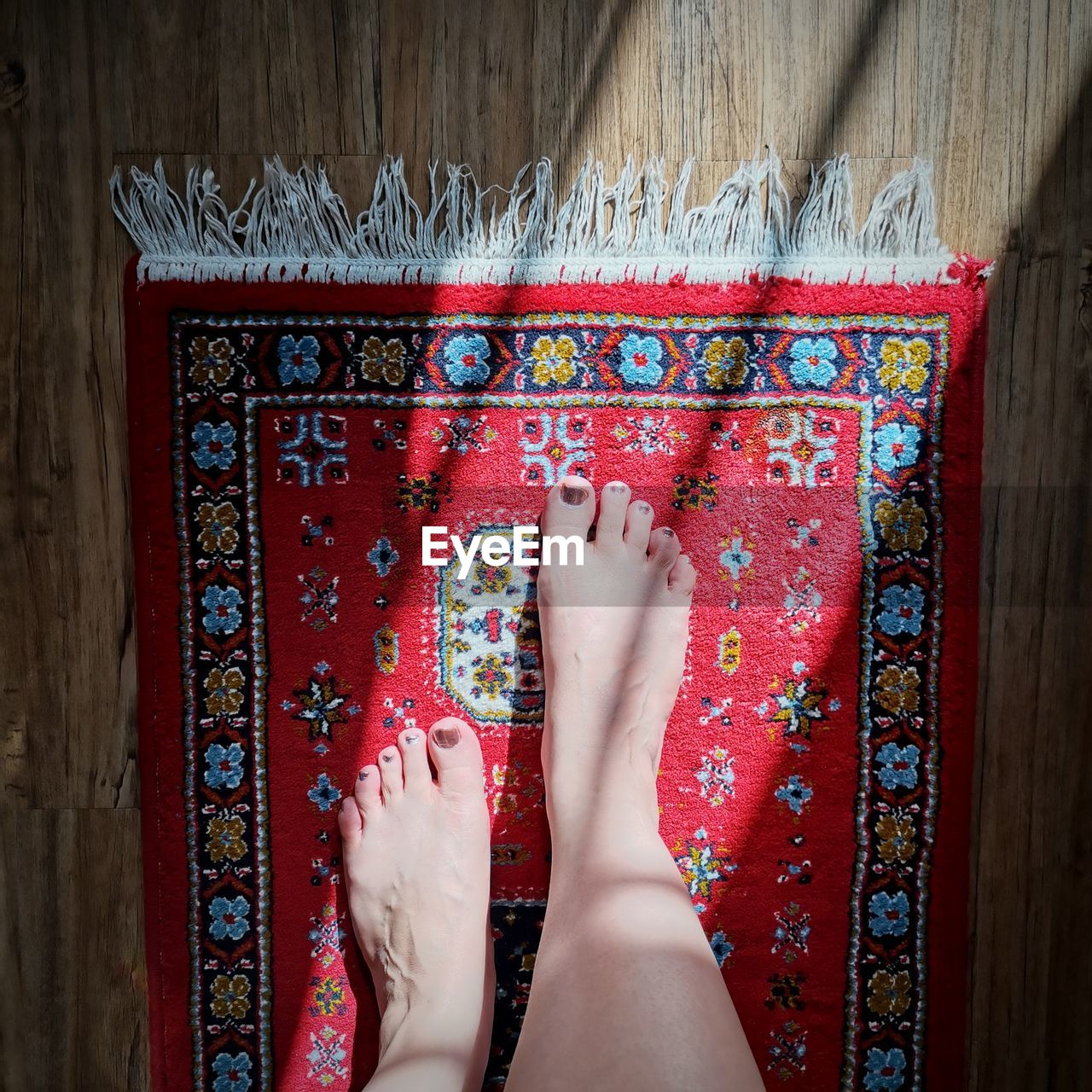 Low section of woman standing barefoot on carpet