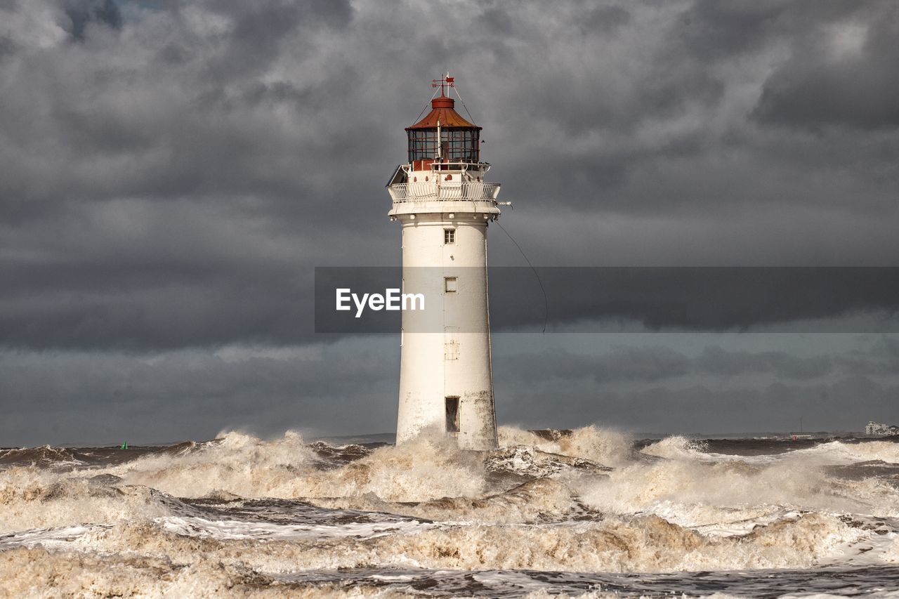 Lighthouse in sea against sky