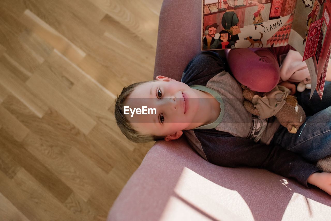 Areal view of a boy sitting on a chair reading at home