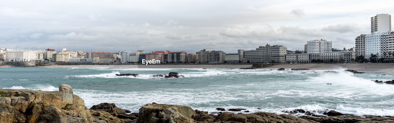 Scenic view of sea and cityscape against sky