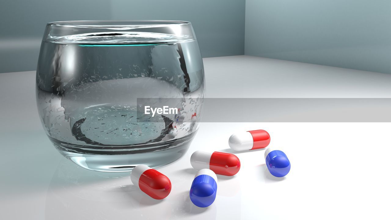 Close-up of medicines by drinking glass on table