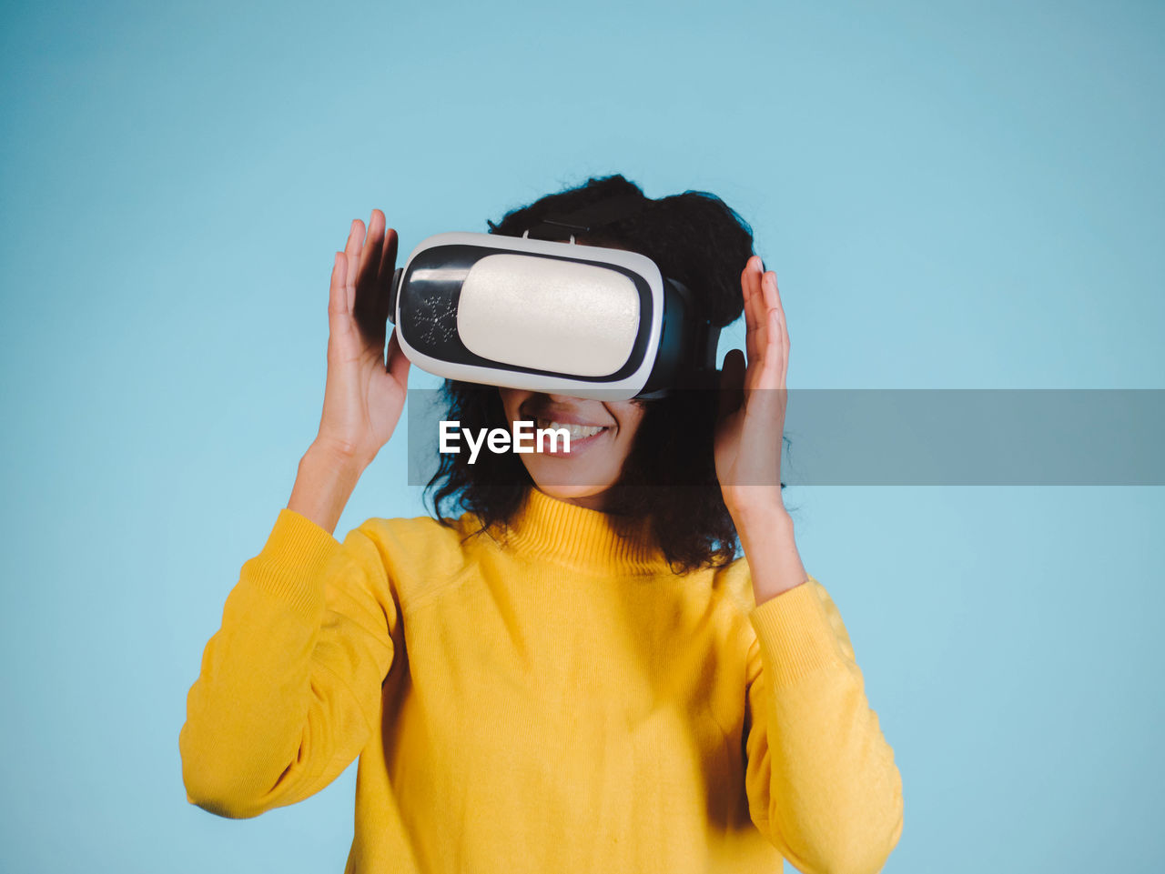 Smiling woman using vr glasses against blue background