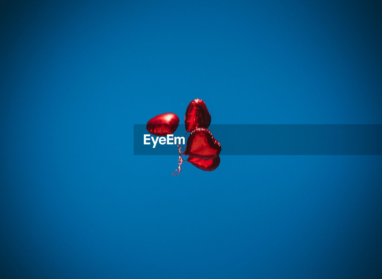 LOW ANGLE VIEW OF RED BALLOON AGAINST BLUE SKY