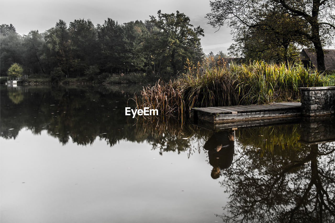Digital composite image of man reflecting in lake