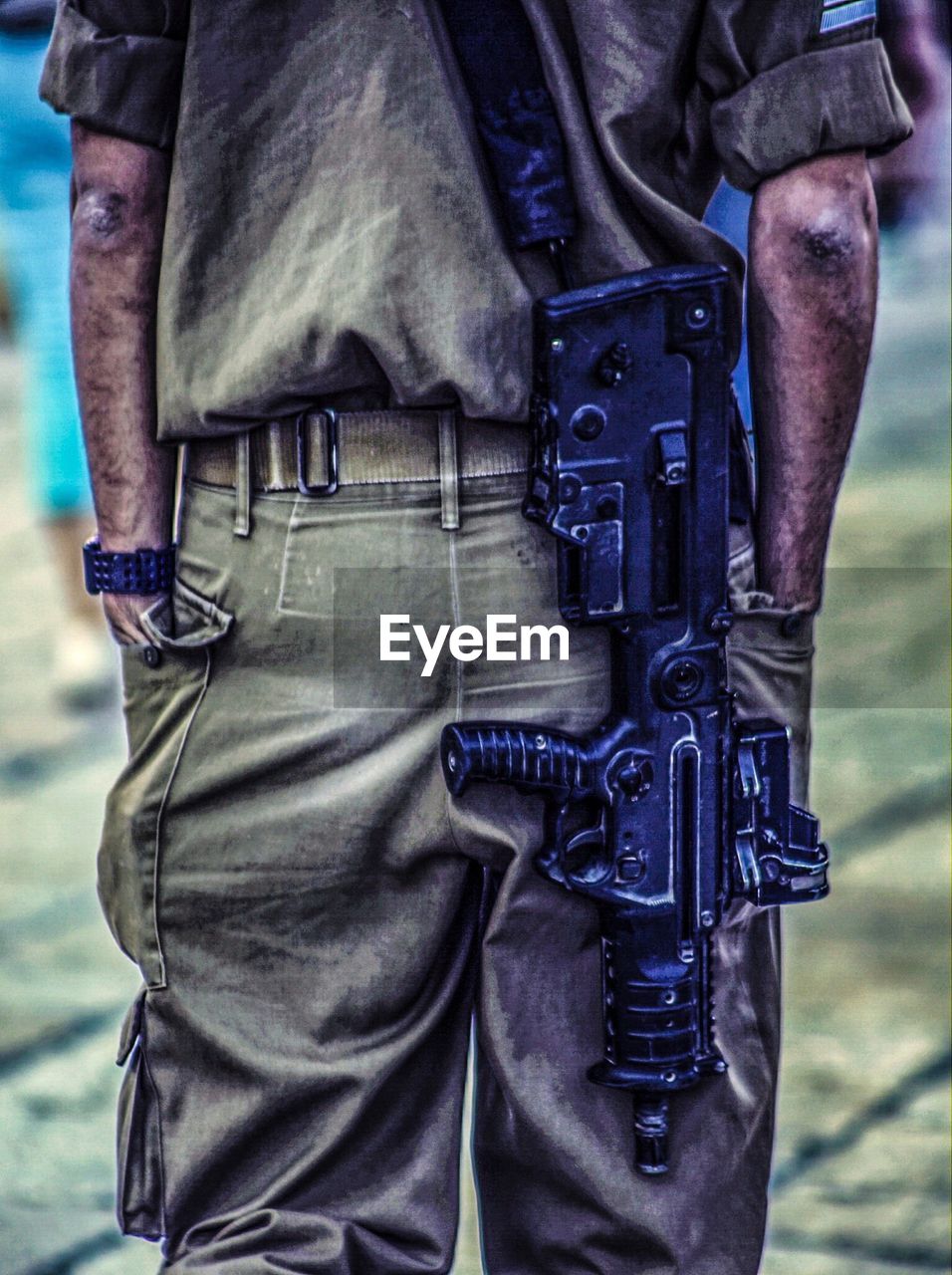 Midsection rear view of soldier with gun in field