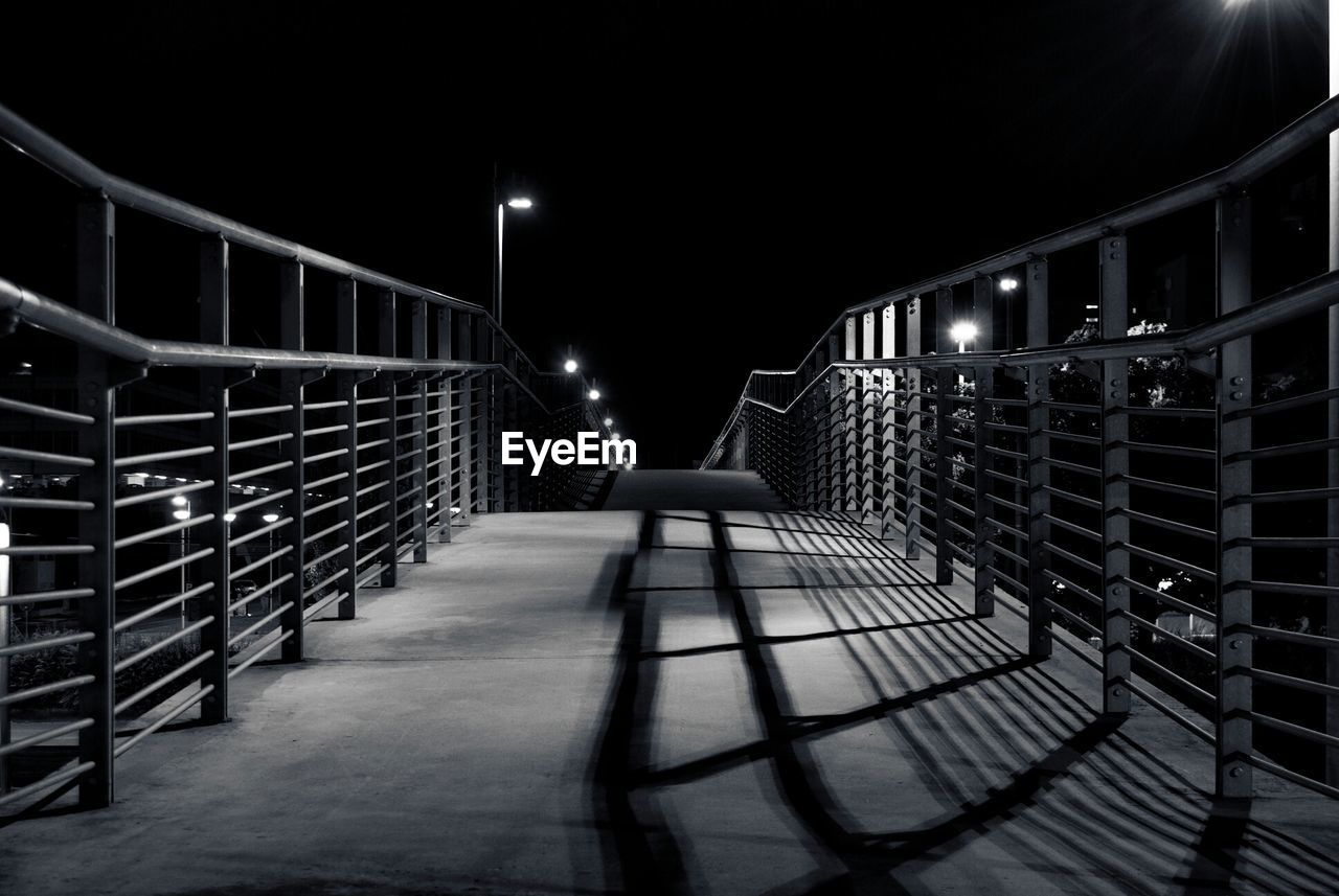 Walkway leading towards steps against sky at night