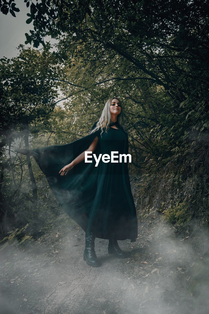 Woman standing by tree in forest