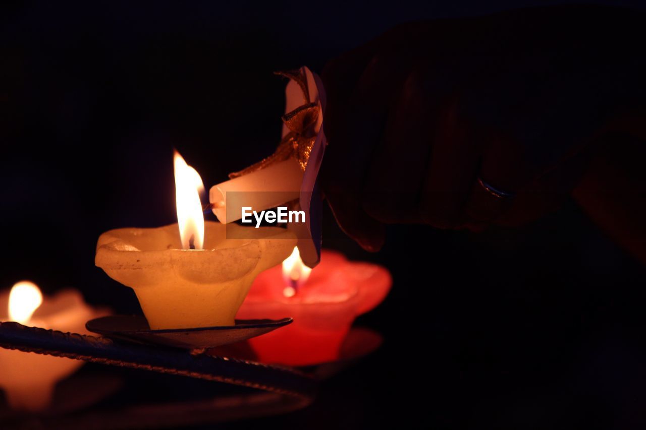 CLOSE-UP OF LIT CANDLES ON DARKROOM