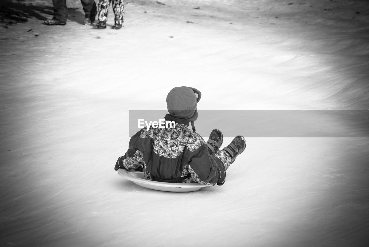 Rear view of boy tobogganing on snow