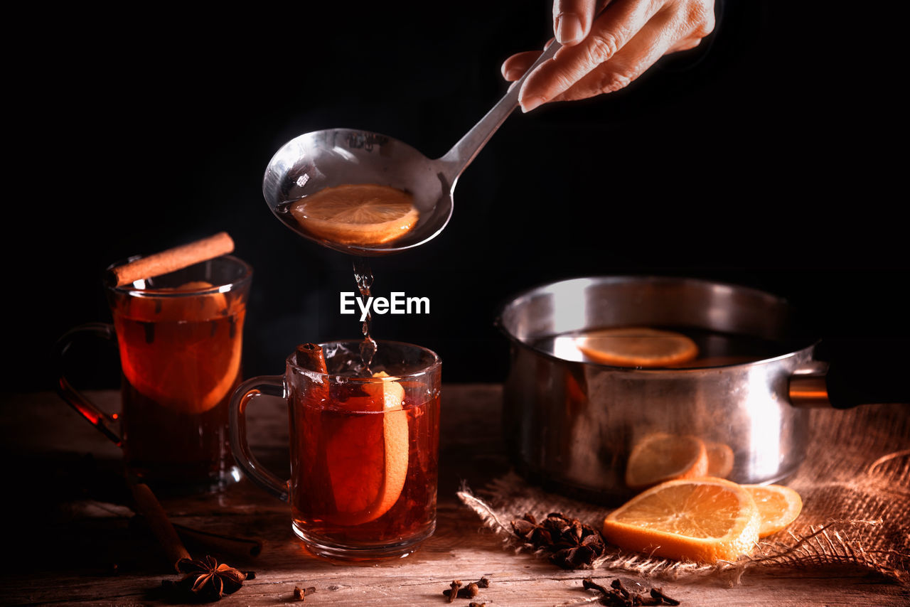 Close-up of drink with spices on table against black background