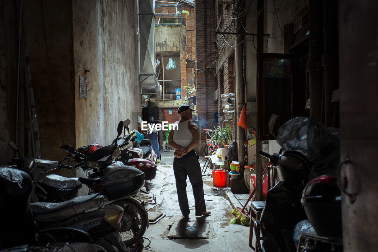 Full length rear view of man standing on footpath amidst buildings