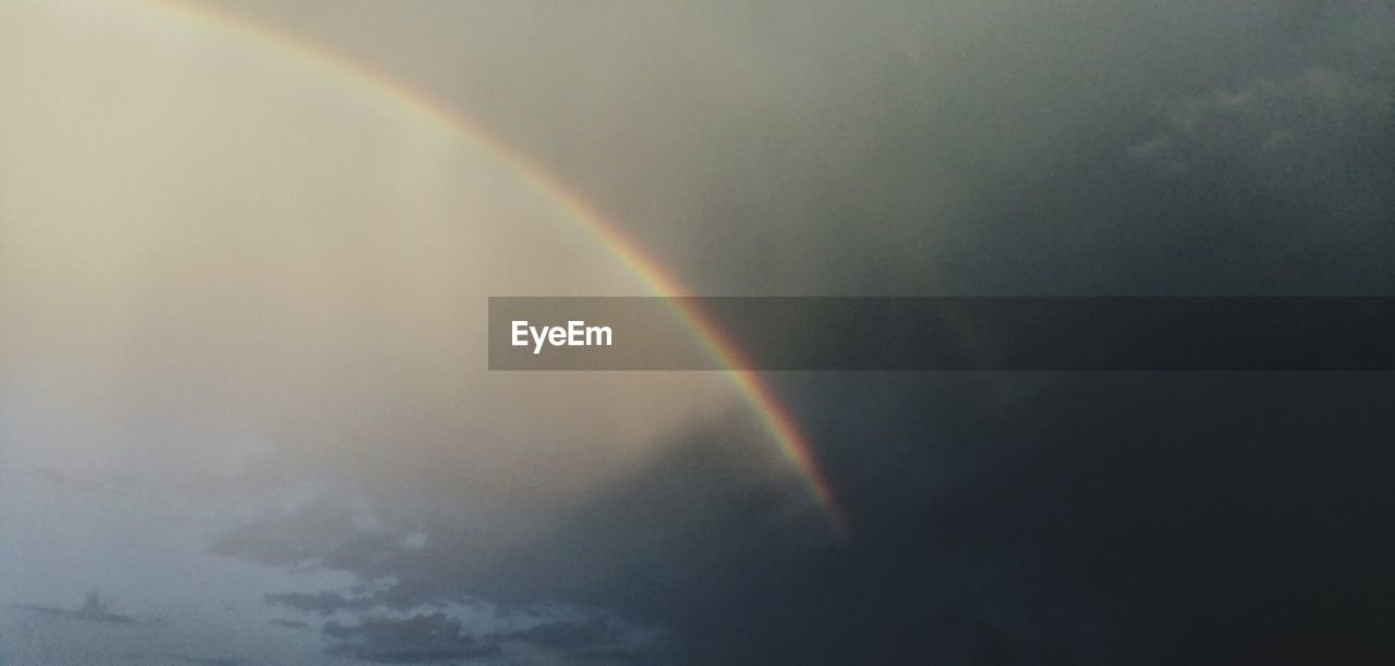 LOW ANGLE VIEW OF RAINBOW AGAINST SKY DURING RAINY SEASON