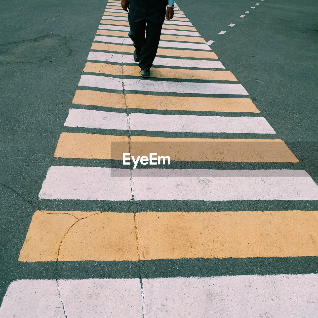 Low section of man walking on zebra crossing