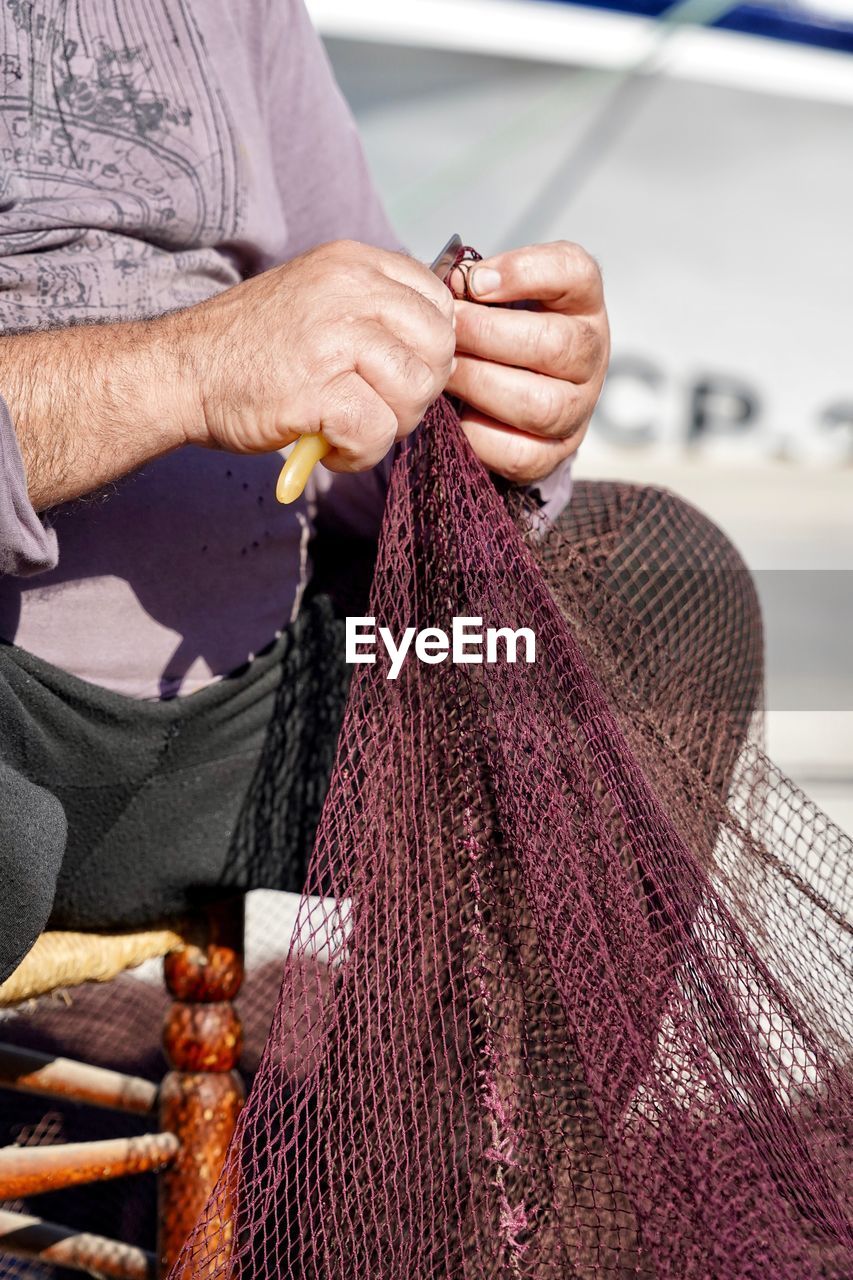 Midsection of man holding fishing net