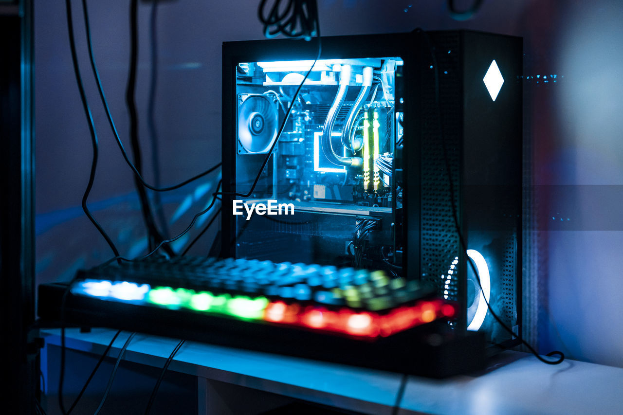 Illuminated computer keyboard and cpu on table in studio