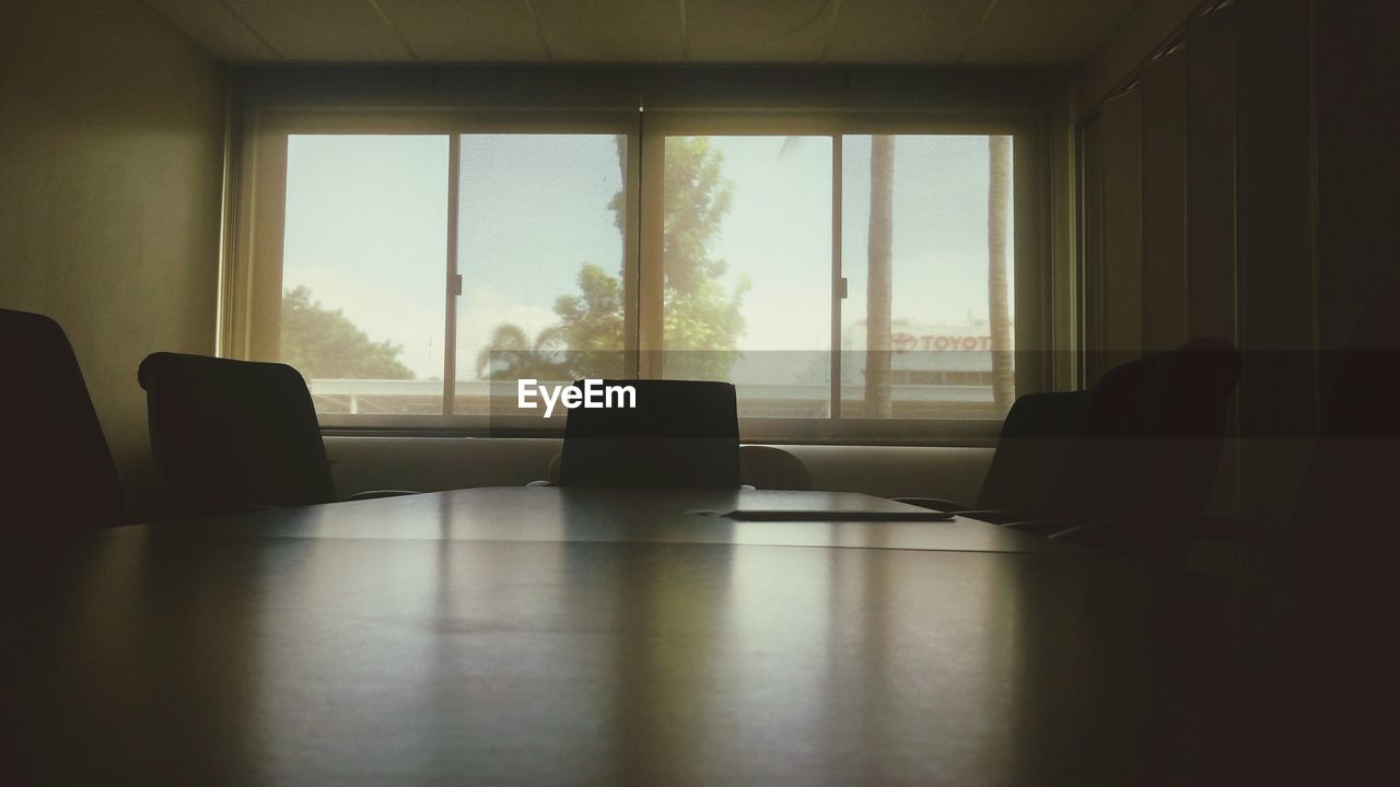 Empty chairs and table against window in board room