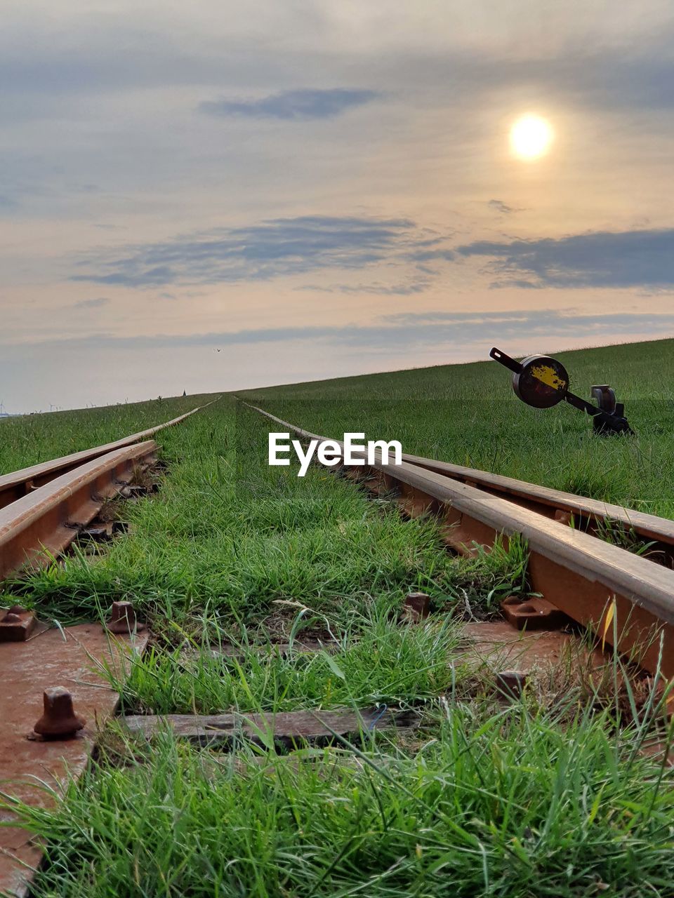 Scenic view of field  and railroad track against sky during sunset