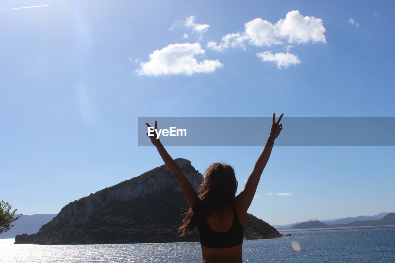 Rear view of woman standing in sea against sky