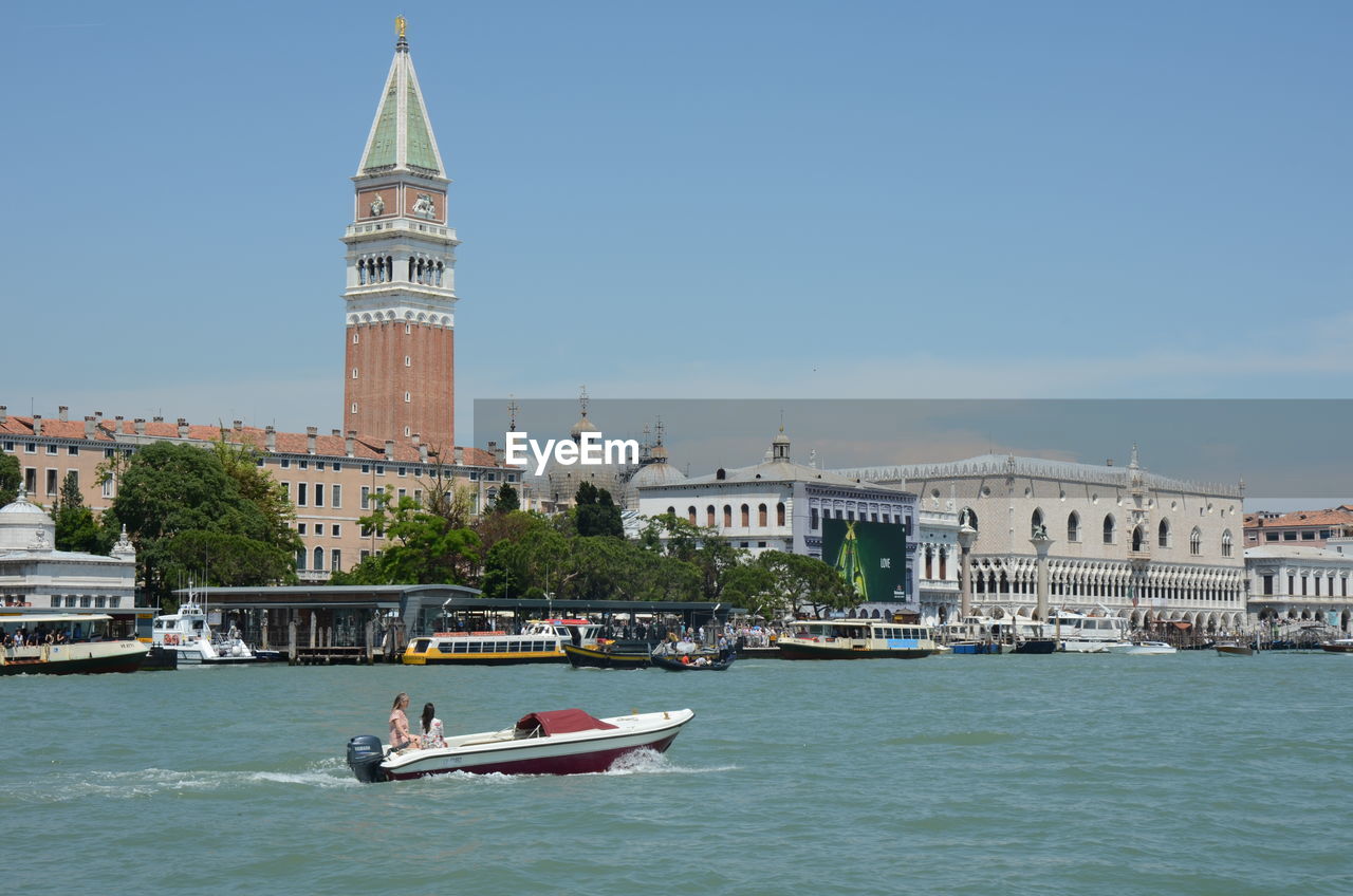 BOATS IN CANAL AMIDST BUILDINGS AGAINST SKY