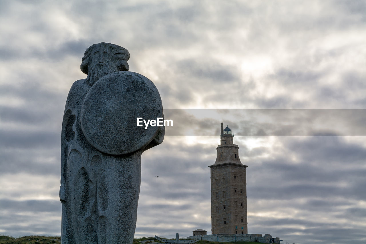 Low angle view of statue against historical building during sunset