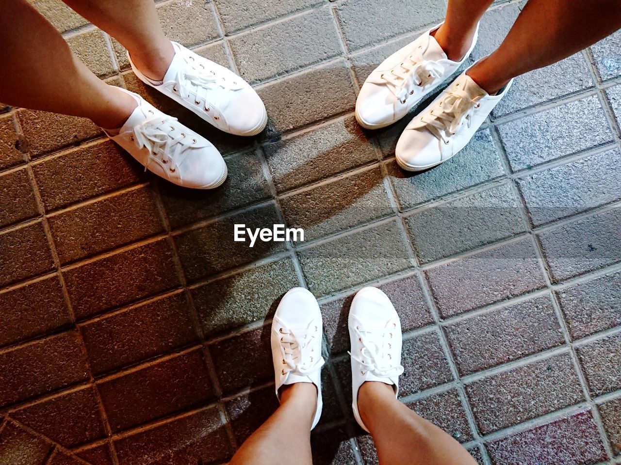 Low section of women standing on tiled floor